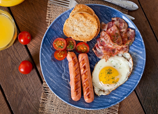 Colazione inglese - toast, uova, pancetta e verdure in stile rustico sul tavolo di legno