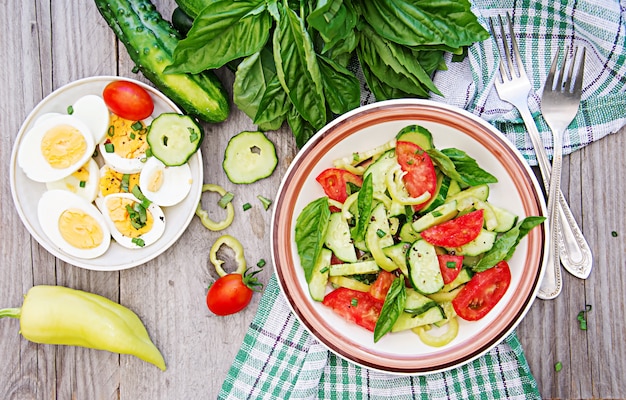 Colazione nel giardino estivo. Insalata di pomodori e cetrioli con cipolle verdi e basilico.