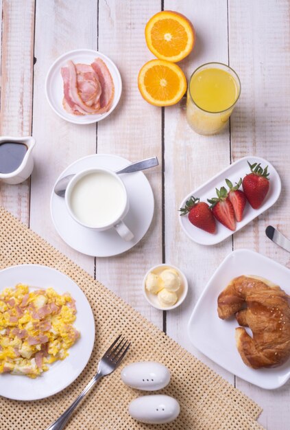 Colazione perfetta per gli amanti del cibo sano: uova strapazzate con prosciutto, latte, caffè, croissant