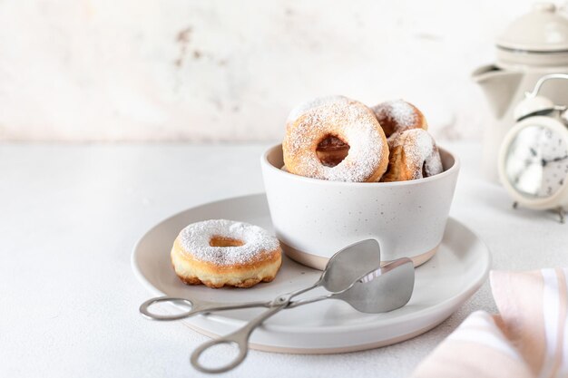 Colazione tradizionale di una ciambella con zucchero e latte o caffè su sfondo bianco Messa a fuoco selettiva