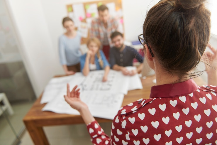 Foto gratuito collaboratori in ufficio con progetti di architettura e un computer