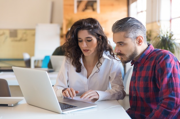 Collaboratori seri che discutono insieme del progetto e che utilizzano computer portatile