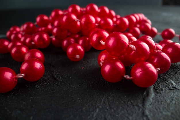 Collana rossa vista frontale su bacche di frutta con foto a colori scuri