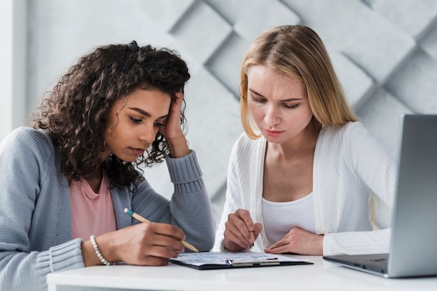 Colleghe bionde ed etniche che pensano al compito di lavoro