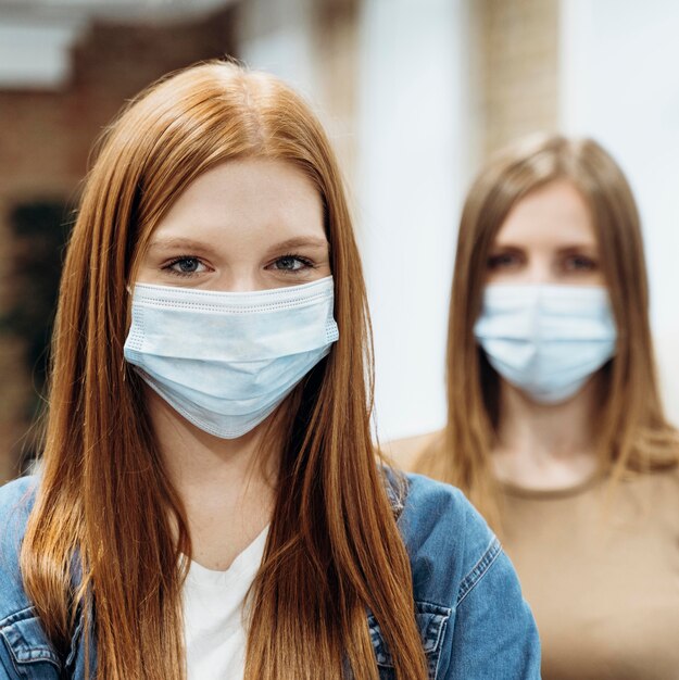 Colleghe di sesso femminile che indossano maschere mediche al lavoro