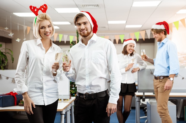 Colleghi che celebrano la festa di Natale in ufficio bevendo champagne sorridente.