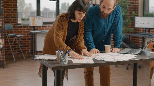 Colleghi che discutono sulla pianificazione del progetto e sulla strategia di marketing, lavorando insieme per affari. Uomo e donna che fanno lavoro di squadra con laptop e documenti per progettare la presentazione.