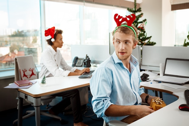 Colleghi che lavorano in ufficio il giorno di Natale dando regali.