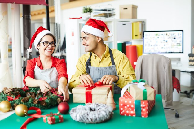 Colleghi che preparano decorazioni natalizie e confezionano regali