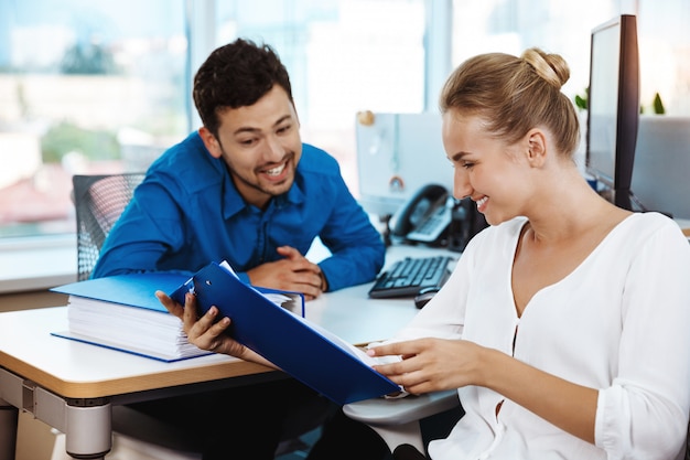 Colleghi che sorridono, parlano, esaminano la cartella, oltre l'ufficio