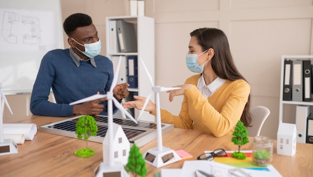 Colleghi con maschere che lavorano insieme al progetto ambientale