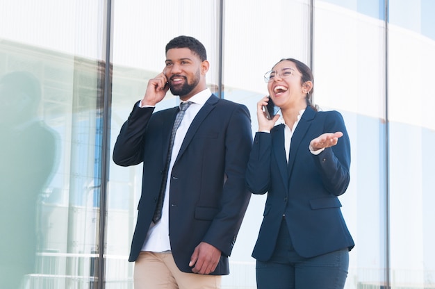 Colleghi di affari eccitati felici che godono colloqui telefonici divertenti