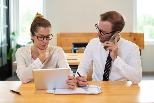 Colleghi di lavoro che lavorano e che utilizzano i dispositivi.