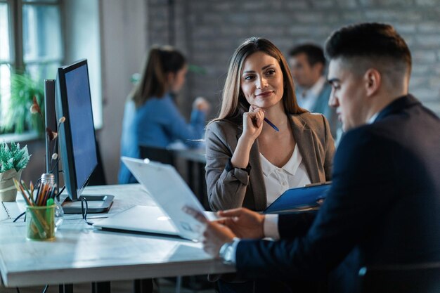 Colleghi di lavoro che lavorano sui rapporti e comunicano mentre lavorano in ufficio Il focus è sulla donna