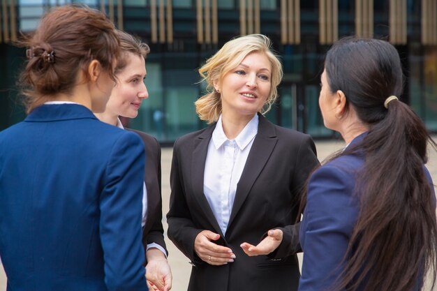 Colleghi di lavoro femminili che discutono del progetto all'aperto. Donne di affari che indossano abiti in piedi insieme in città e parlando. Concetto di comunicazione