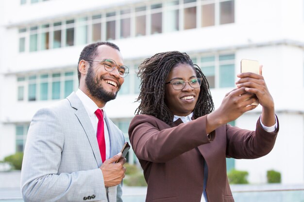 Colleghi felici di affari che prendono selfie fuori