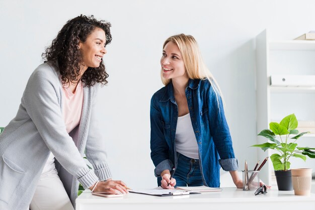 Colleghi femminili amichevoli che discutono lavoro e che ridono dell&#39;ufficio