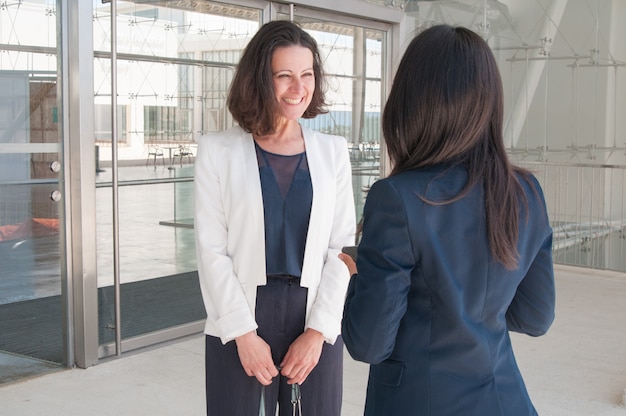 Colleghi femminili felici che parlano nell&#39;ufficio corridoio