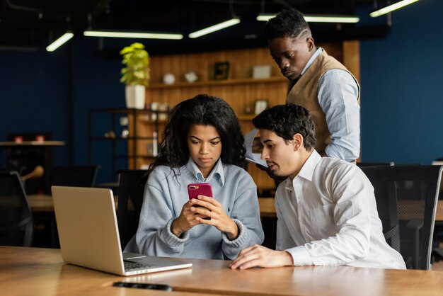 Colleghi in ufficio che lavorano con laptop e smartphone