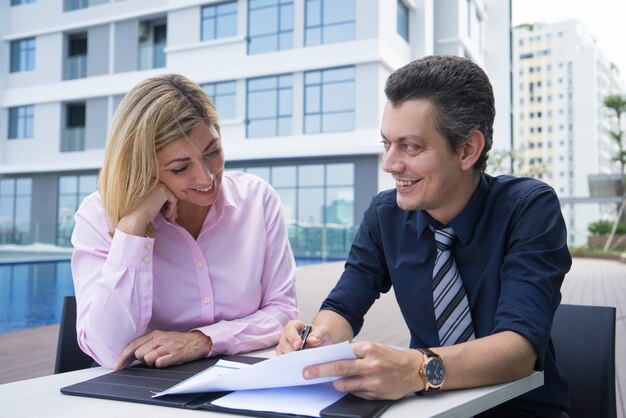 Colleghi intraprendenti positivi che elaborano strategia mentre osservando rapporto nel caffè della città