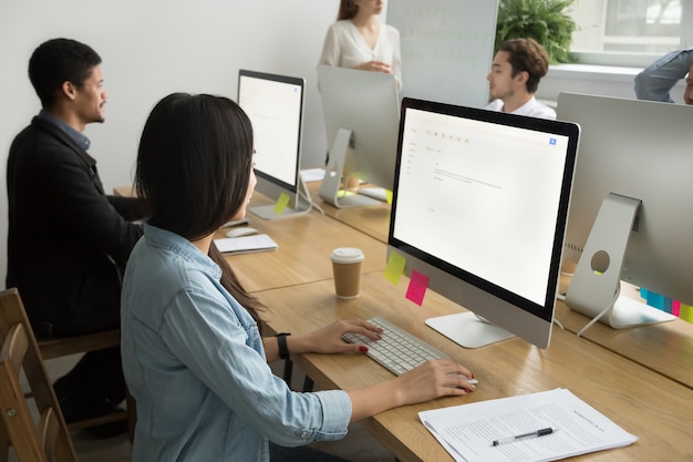Colleghi multirazziali che lavorano insieme su computer desktop in ufficio aziendale