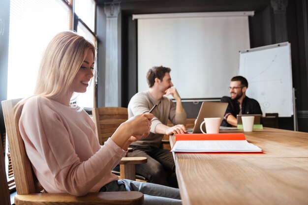 Colleghi seri seduti in ufficio e utilizzando laptop e telefono