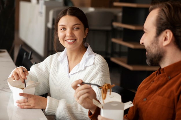 Colleghi sorridenti che mangiano noodles durante la pausa