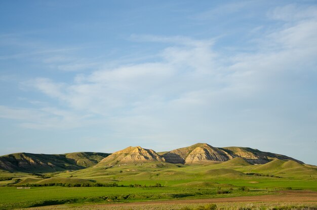 Colline e montagne che brillano sotto il cielo nuvoloso blu