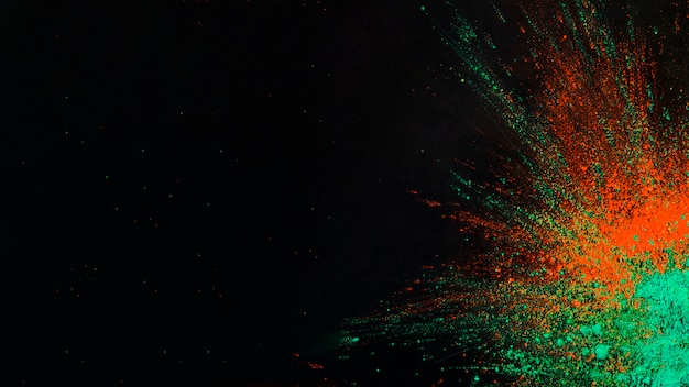 Colori holi verdi e arancioni su un angolo di sfondo nero