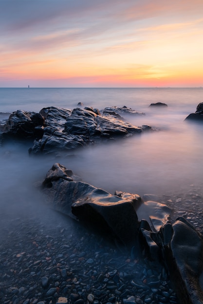 Colpo a lunga esposizione del paesaggio marino a Guernsey durante un tramonto