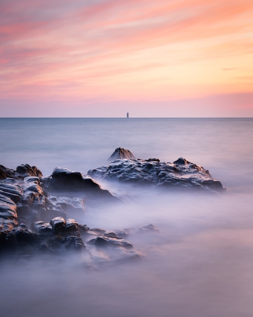 Colpo a lunga esposizione del paesaggio marino a Guernsey durante un tramonto