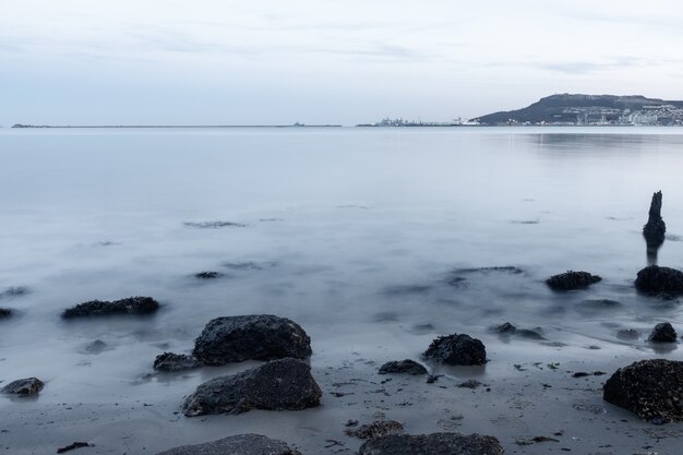 Colpo a lunga esposizione delle pietre sulla riva vicino a Portland, Weymouth, Dorset, Regno Unito