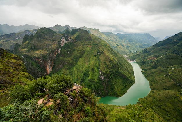 Colpo aereo di un fiume stretto nelle montagne sotto il cielo nuvoloso nel Vietnam