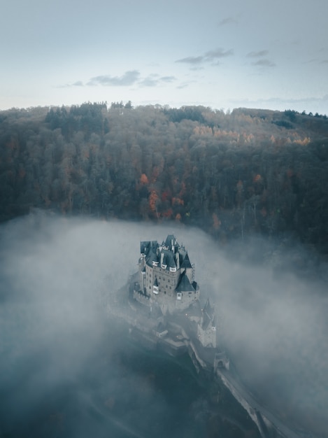 Colpo aereo verticale del castello di Eltz circondato con le nuvole e gli alberi in Germania