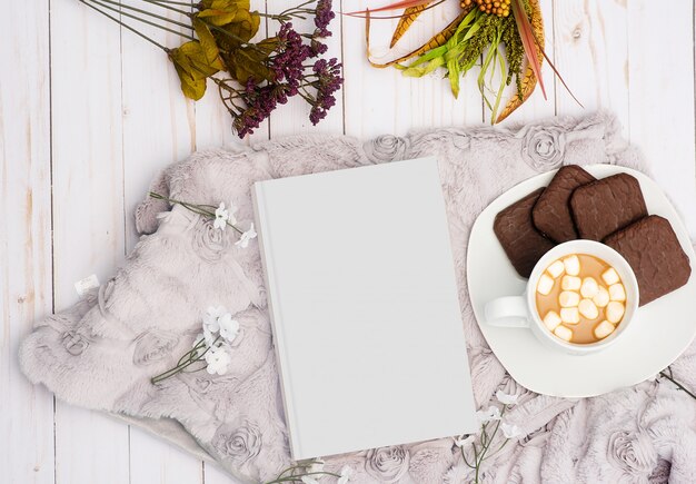 Colpo ambientale di un libro bianco accanto a una bevanda dolce con i biscotti del cioccolato su un piatto