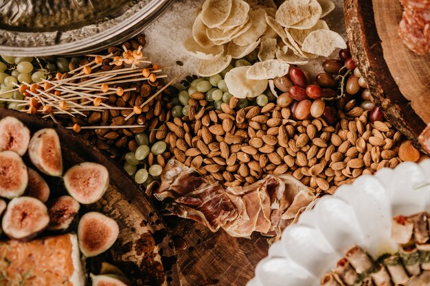 Colpo dall'alto di un tavolo pieno di mandorle, prosciutto, fichi e frutta secca