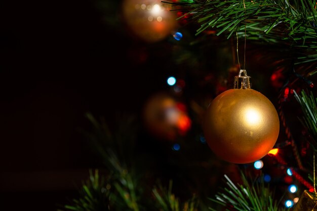 Colpo del primo piano degli ornamenti dorati sull'albero di Natale decorato