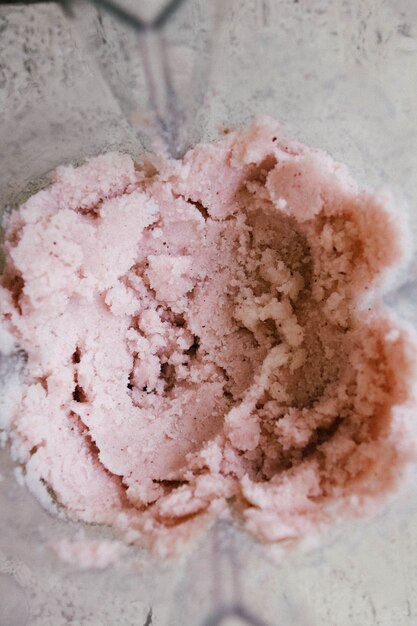 Colpo del primo piano del gelato fruttato rosa mescolato schiacciato con una rosa