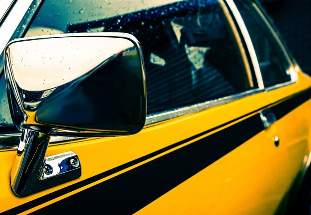Colpo del primo piano del lato di un'auto gialla con una linea nera sotto i finestrini
