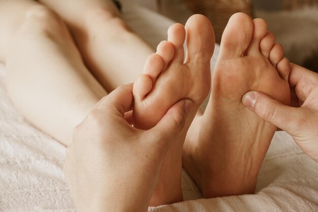 Colpo del primo piano del massaggiatore che massaggia i piedi di una donna