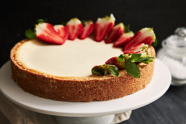 Colpo del primo piano dell'angolo alto di una torta di formaggio della fragola su un piatto bianco