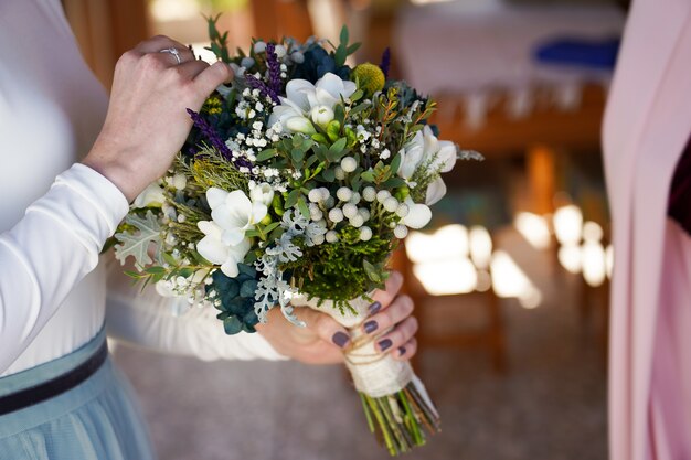 Colpo del primo piano della sposa che tiene il bouquet con bellissimi fiori
