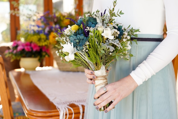 Colpo del primo piano della sposa che tiene il bouquet con bellissimi fiori