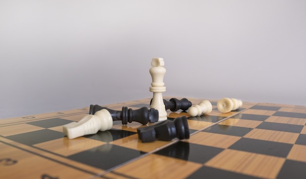 Colpo del primo piano delle figurine di scacchi su una scacchiera con uno sfondo bianco sfocato