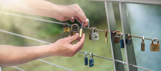 Colpo del primo piano delle mani che appendono le serrature su una corda - concetto di amore