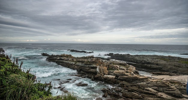 Colpo del primo piano delle rocce su una spiaggia sotto un cielo pieno di nuvole