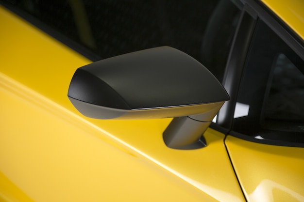 Colpo del primo piano dello specchietto laterale nero di un'auto sportiva moderna gialla