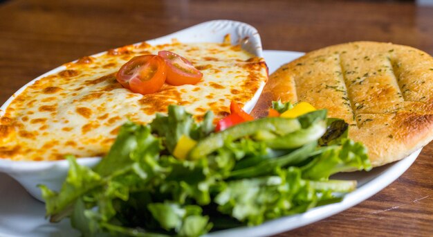 Colpo del primo piano di cannelloni con focaccia all'aglio e insalata