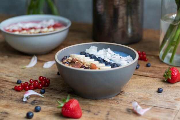 Colpo del primo piano di ciotole per frullati sani con frutta e muesli