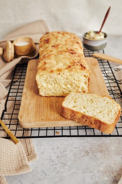 Colpo del primo piano di delizioso pane al formaggio con burro alle erbe su un tavolo bianco